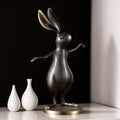 Stylized brass rabbit figurine on table with vases