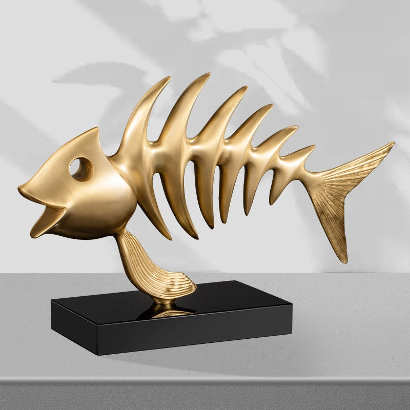 Side profile of gold fish skeleton statue on black base