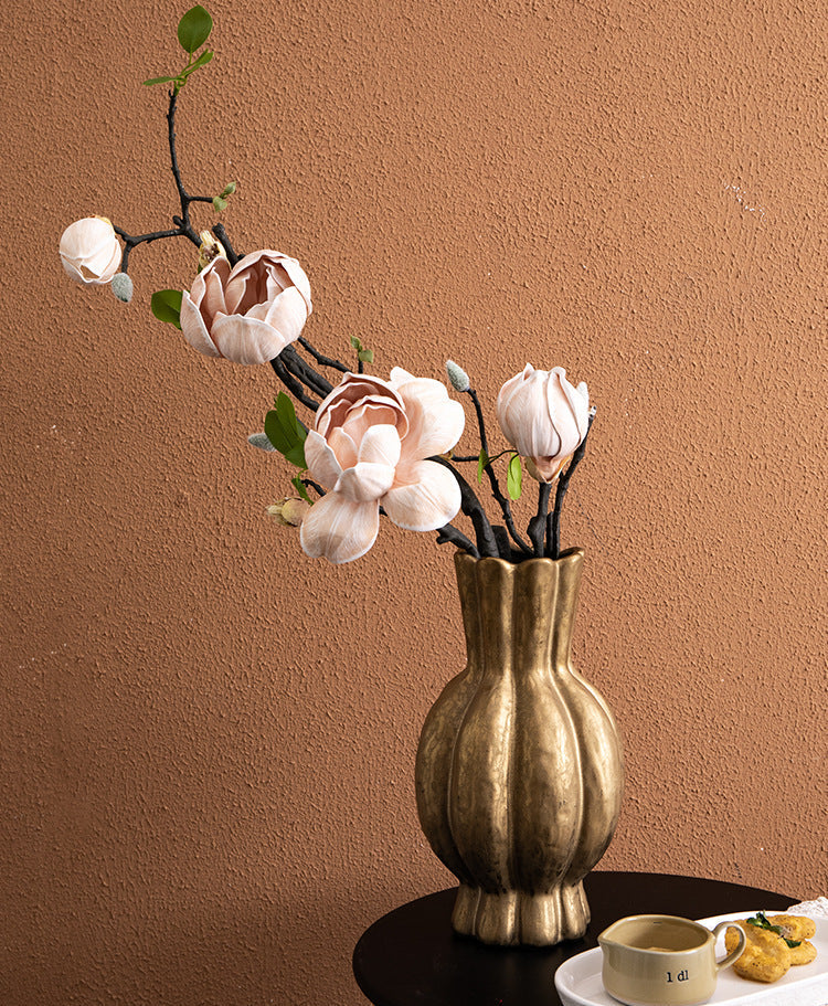 Burnished gold ribbed vase holding magnolia flowers