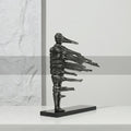 Side profile of antique silver wind-swept figure sculpture on black base