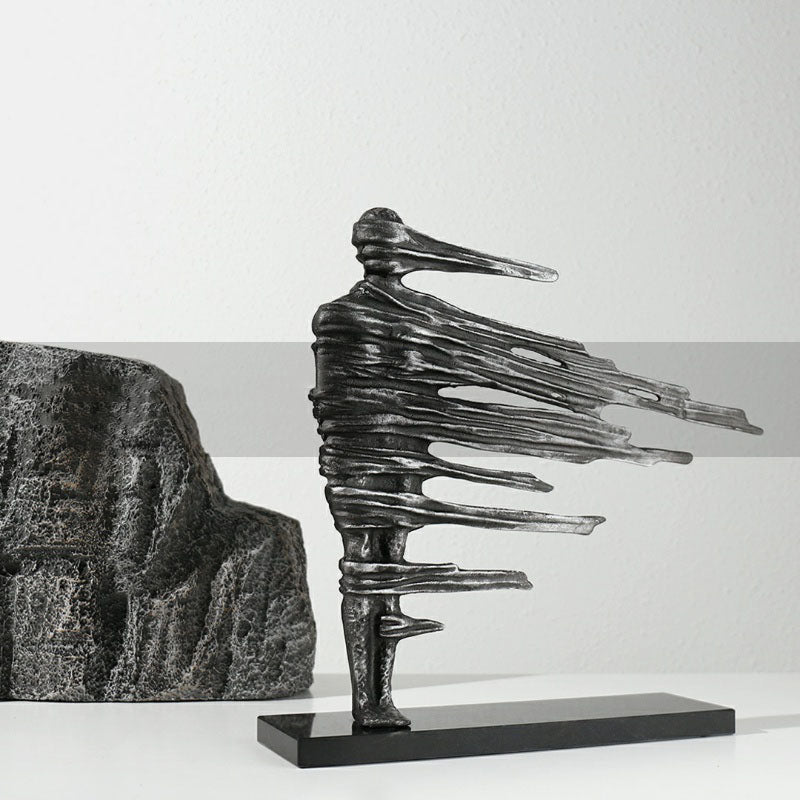 Angled view of distressed metal abstract figure sculpture with rock background