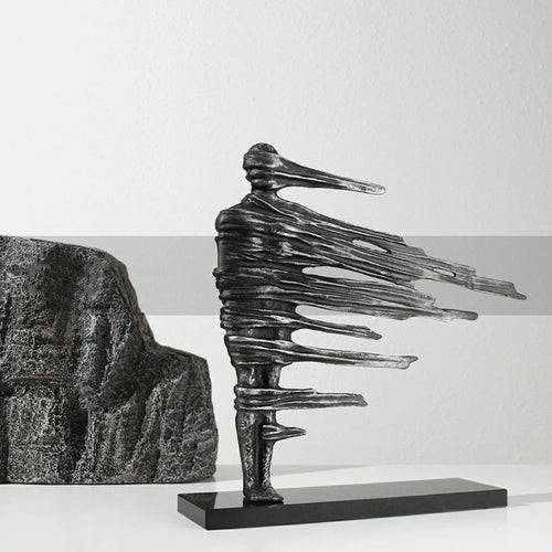 Angled view of distressed metal abstract figure sculpture with rock background