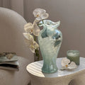 Aqua swirl glass vase with white orchids on terrazzo table