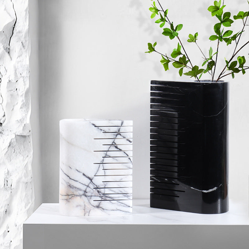 Styled interior shot featuring both the large black and medium white ribbed marble vases with greenery