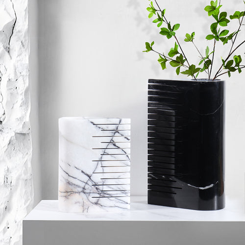 Styled interior shot featuring both the large black and medium white ribbed marble vases with greenery