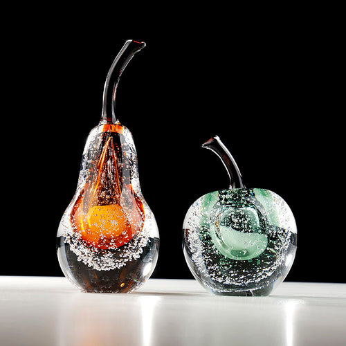 Amber and green art glass fruit sculptures set on white surface