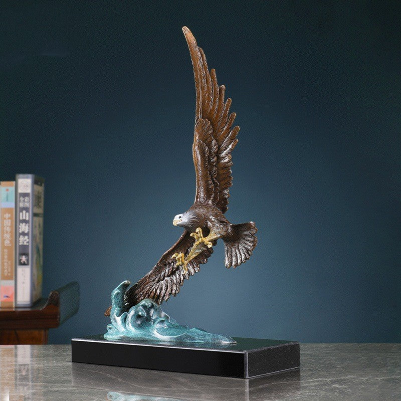 Angled view of metal eagle catching fish on stylized wave base