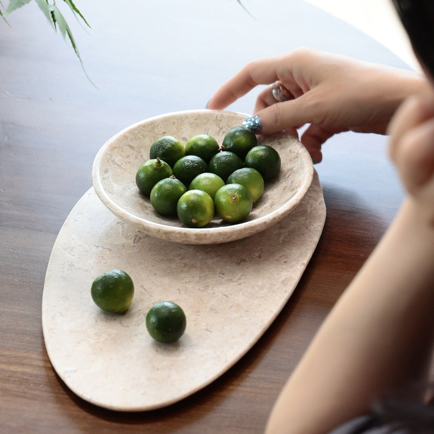 High angle view of beige marble bowl and tray set with limes