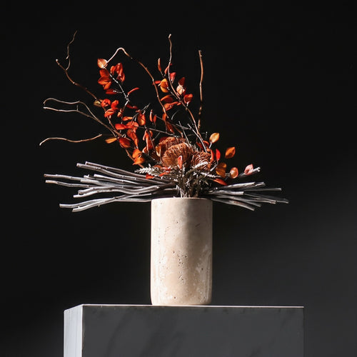 Tall beige marble vase with dry red floral arrangement