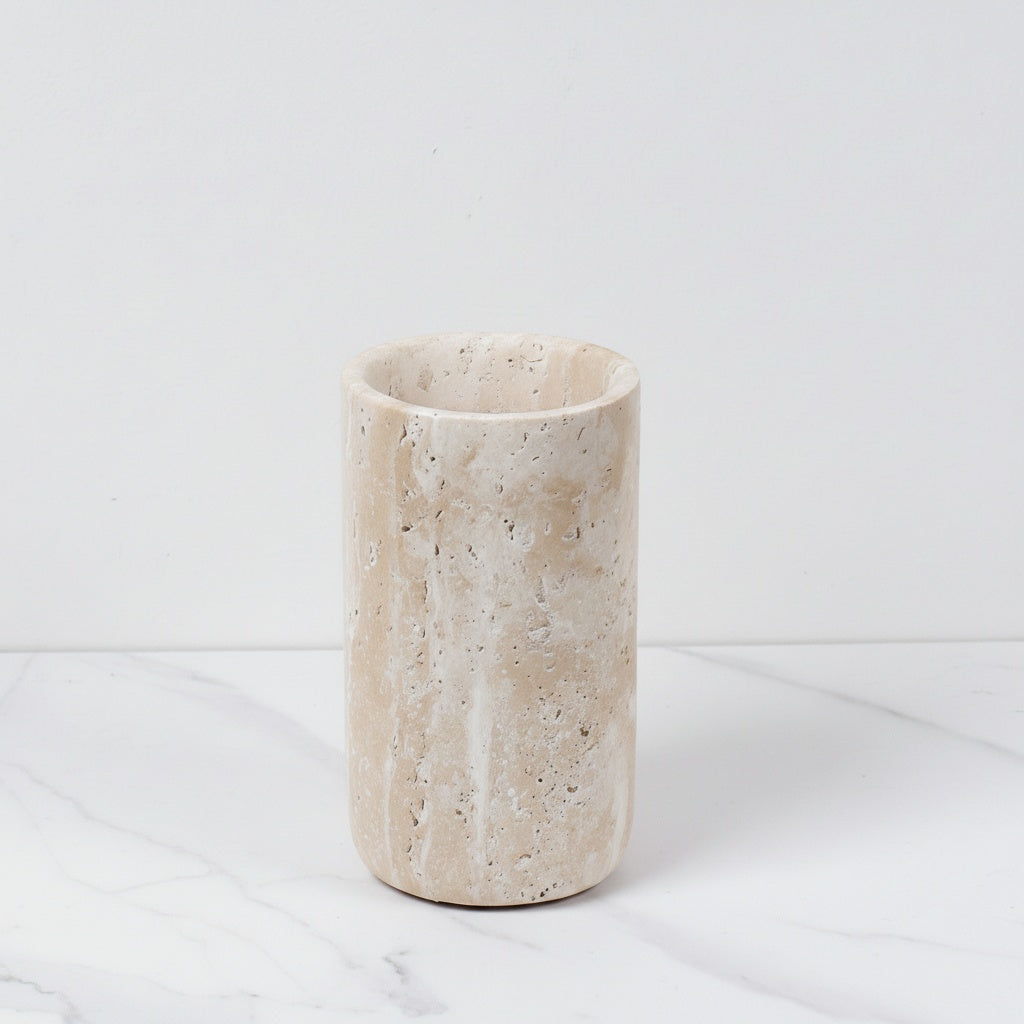 Empty tall beige travertine marble cylinder vase on white surface