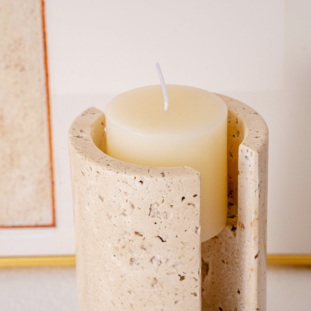 Close-up detail of beige travertine stone texture and porous surface with a lit white pillar candle