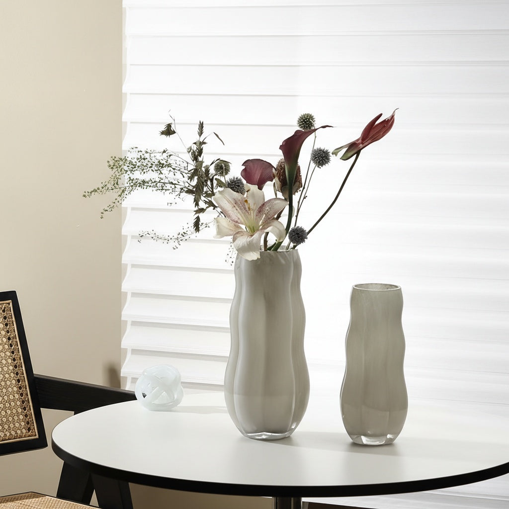 Beige wavy glass vase with flowers on white table