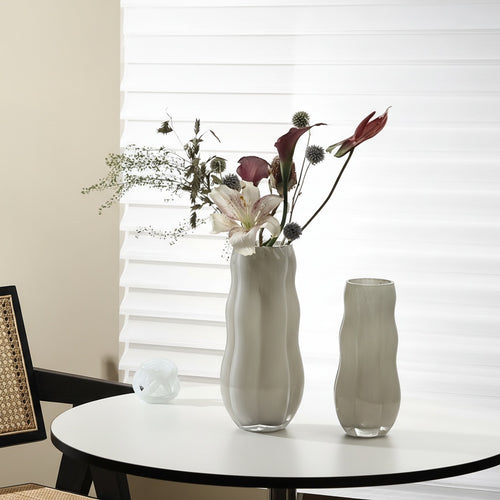 Beige wavy glass vase with flowers on white table