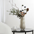 Organic shaped beige glass vase on glass side table