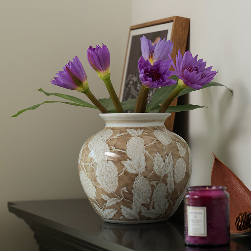 Side view of beige ceramic vase on dark console