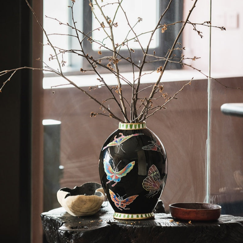 Black ceramic vase with butterfly motif on wooden stand