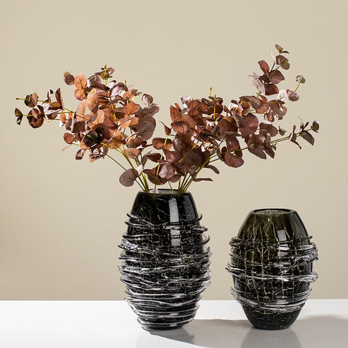 Pair of black crackle glass vases with spiral wrap on white table
