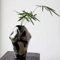 Black and cream abstract ceramic vase with green bamboo foliage