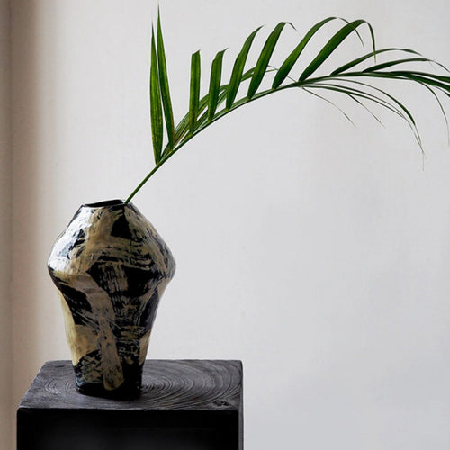 Hand painted black ceramic vase with cream brushstrokes on display