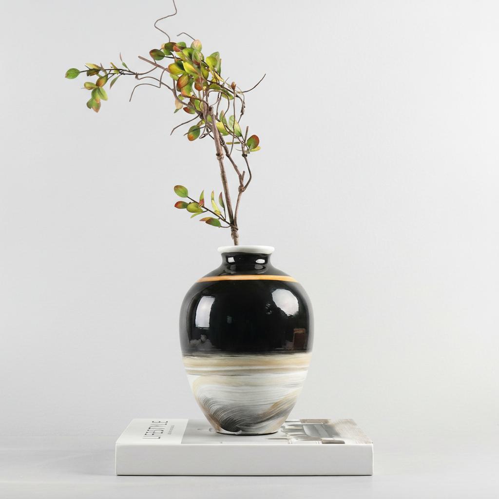 Medium ceramic vase styled on book with greenery