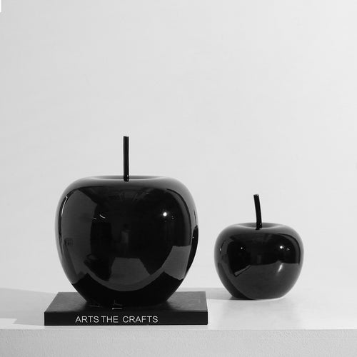 Glossy black ceramic apple sculptures on art book