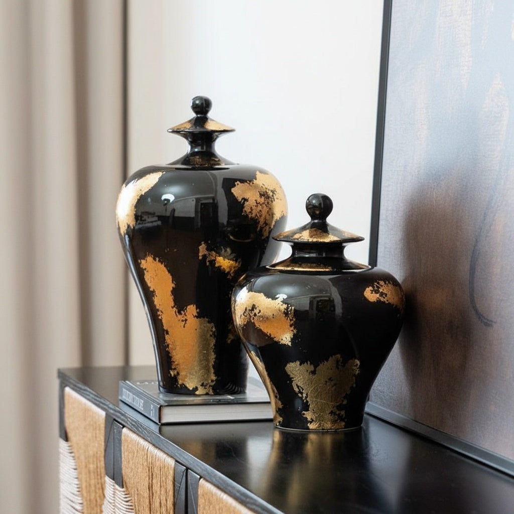 Two black and gold ceramic jars styled on a console table