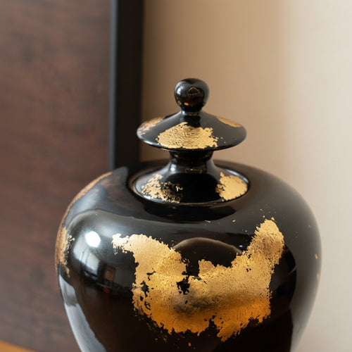 Close up detail of gold leaf texture on black ceramic lid