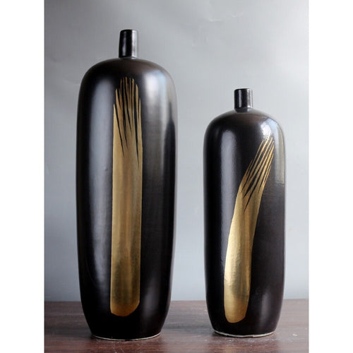Two tall black vases with gold accent design standing side by side
