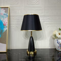 Front view of black and gold teardrop table lamp on marble surface