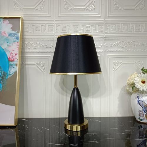 Front view of black and gold teardrop table lamp on marble surface