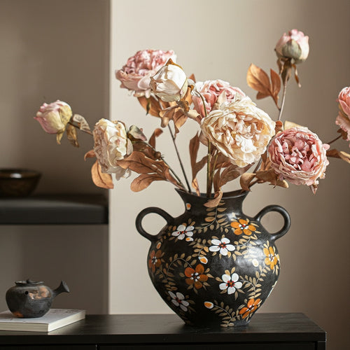 Angled view of floral painted black vase on dark surface