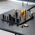 Minimalist black marble and brass chess set on table