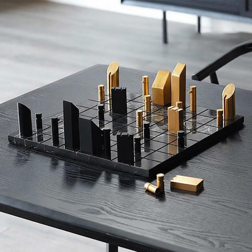 Minimalist black marble and brass chess set on table
