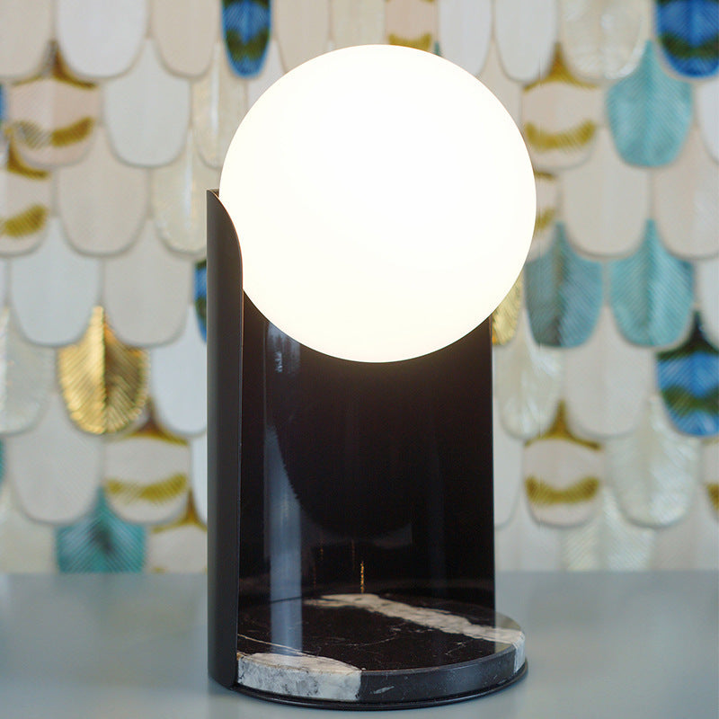 Front view of illuminated black marble curved table lamp