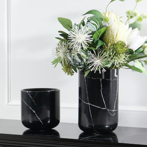 Black marble cylindrical vase with floral arrangement on console