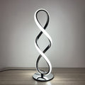 Illuminated black metal spiral LED table lamp on wooden surface