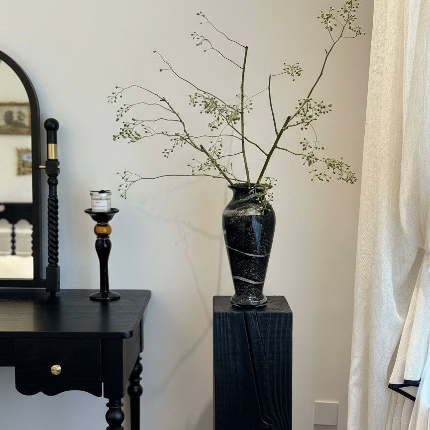 Lifestyle shot of vase on black pedestal with branches