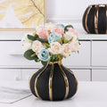 Lifestyle view of black and gold vase with pastel roses