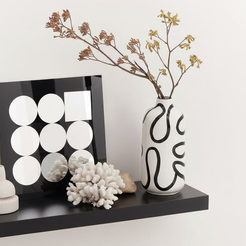 Ceramic vase with dried flowers on shelf with modern decor