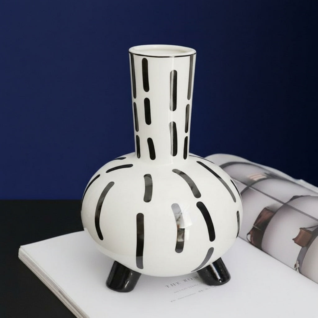 Front view of black and white patterned ceramic footed vase on a book