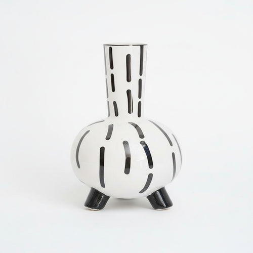 Studio shot of white ceramic vase with black abstract stripes and feet