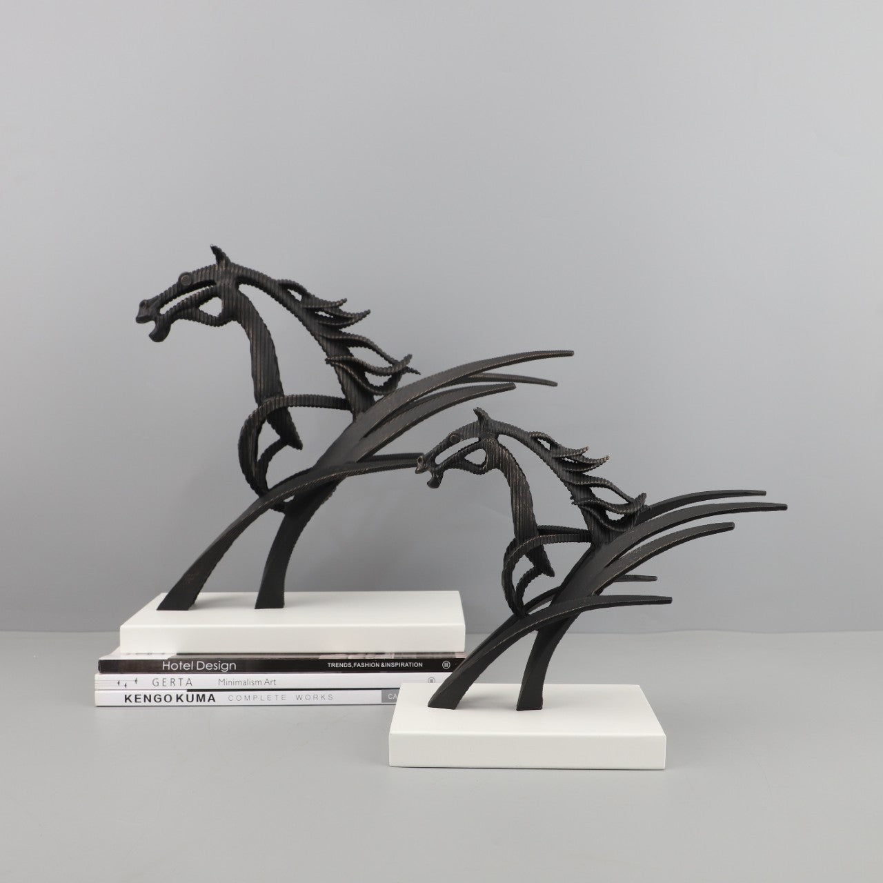 Front view of large and medium abstract metal horse sculptures on white bases