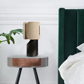 Front view of blackened metal table lamp with linen shade on side table