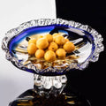 Blue and amber crystal fruit bowl with scalloped rim holding apricots