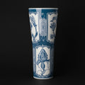 Blue and white ceramic tall flared vase against a dark background