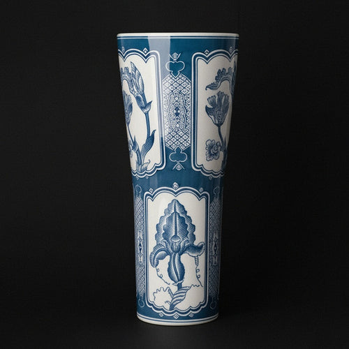 Blue and white ceramic tall flared vase against a dark background