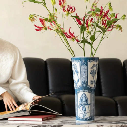 Blue and white ceramic tall flared vase styled with red and yellow flowers on a table