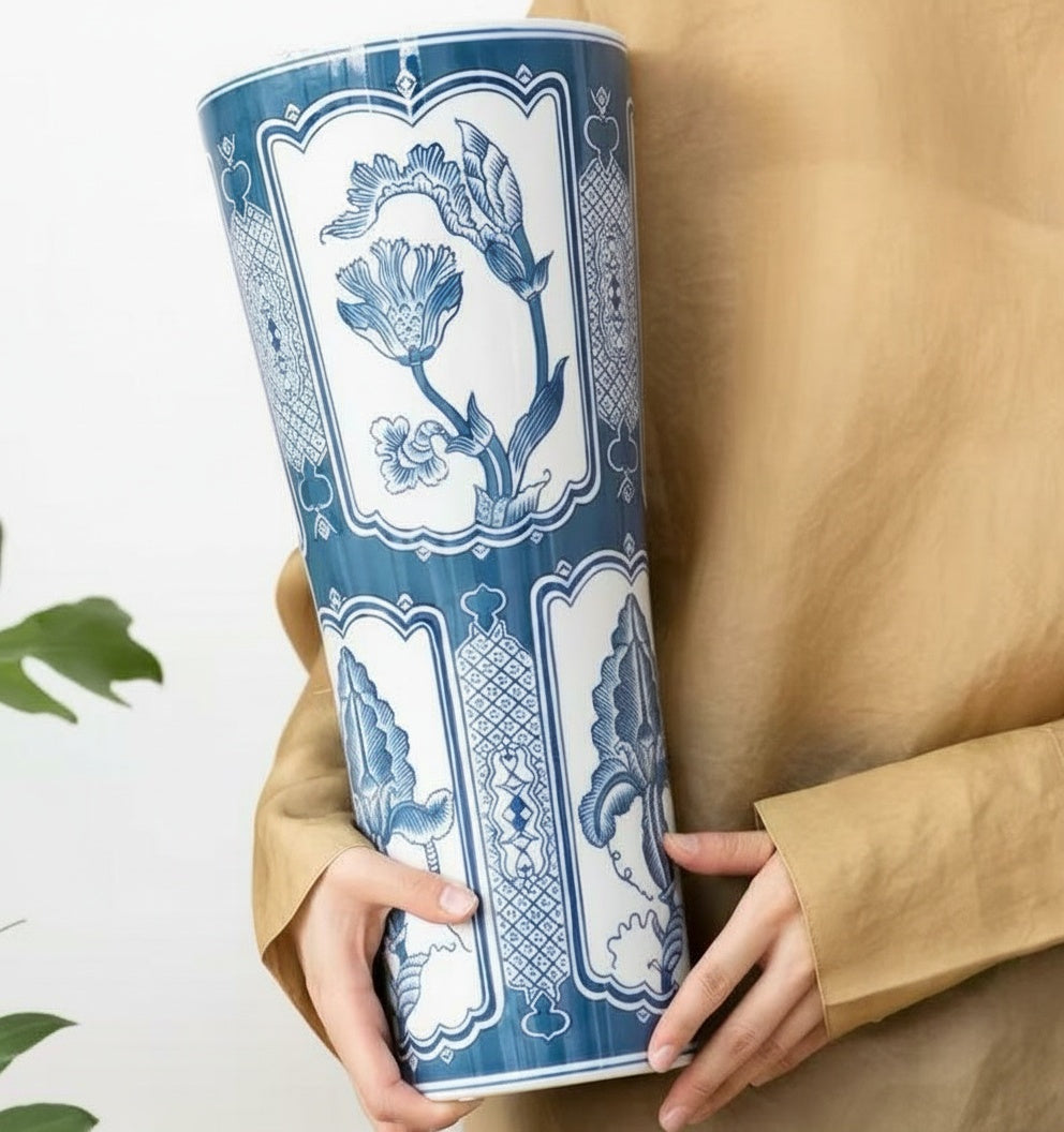 Person holding a blue and white ceramic tall flared vase showing scale