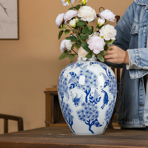 Person arranging flowers in a blue and white porcelain vase