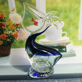 Side profile of blue and clear glass pelican sculpture with red fish detail